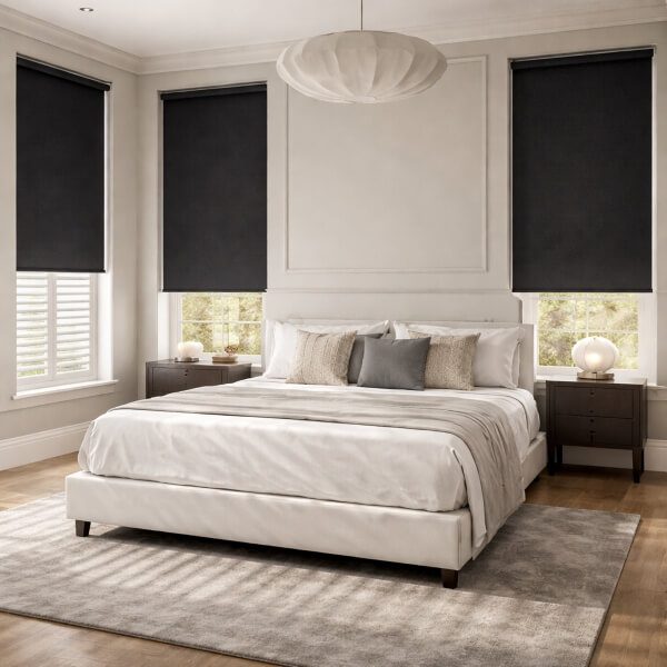 Blackout roller blinds installed in a modern bedroom, partially lowered to reduce light and create a darker, more comfortable sleeping environment.