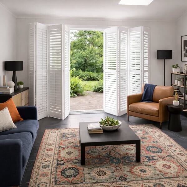 Bright living space styled with practical PVC bifold shutters by Blinds and Shutter Guys