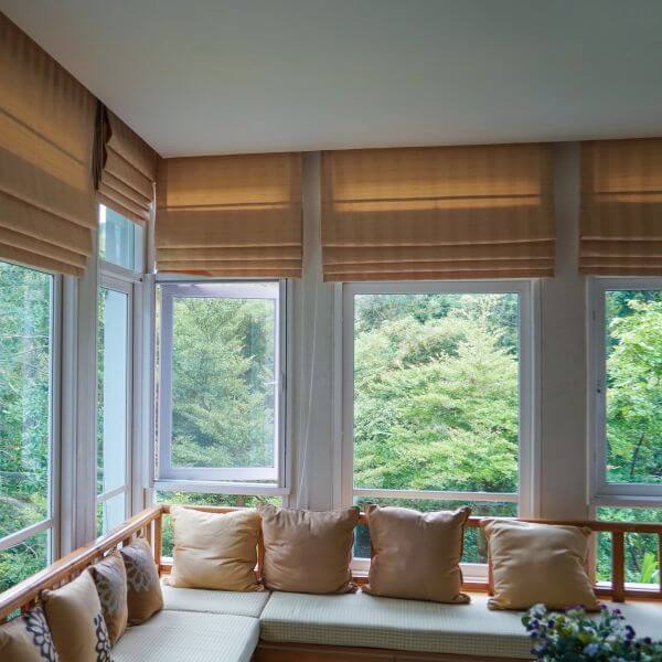 Multiple Roman blinds in a warm natural fabric fitted across corner windows, partially raised to create soft stacked folds, installed by Blinds and Shutter Guys Newcastle