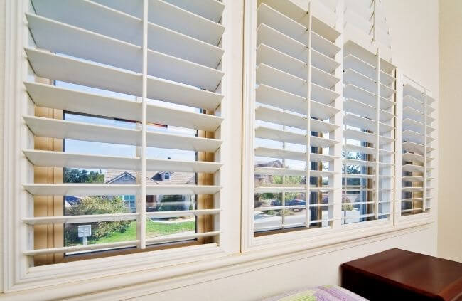 White PVC plantation shutters installed on bedroom windows by Blinds and Shutter Guys Newcastle